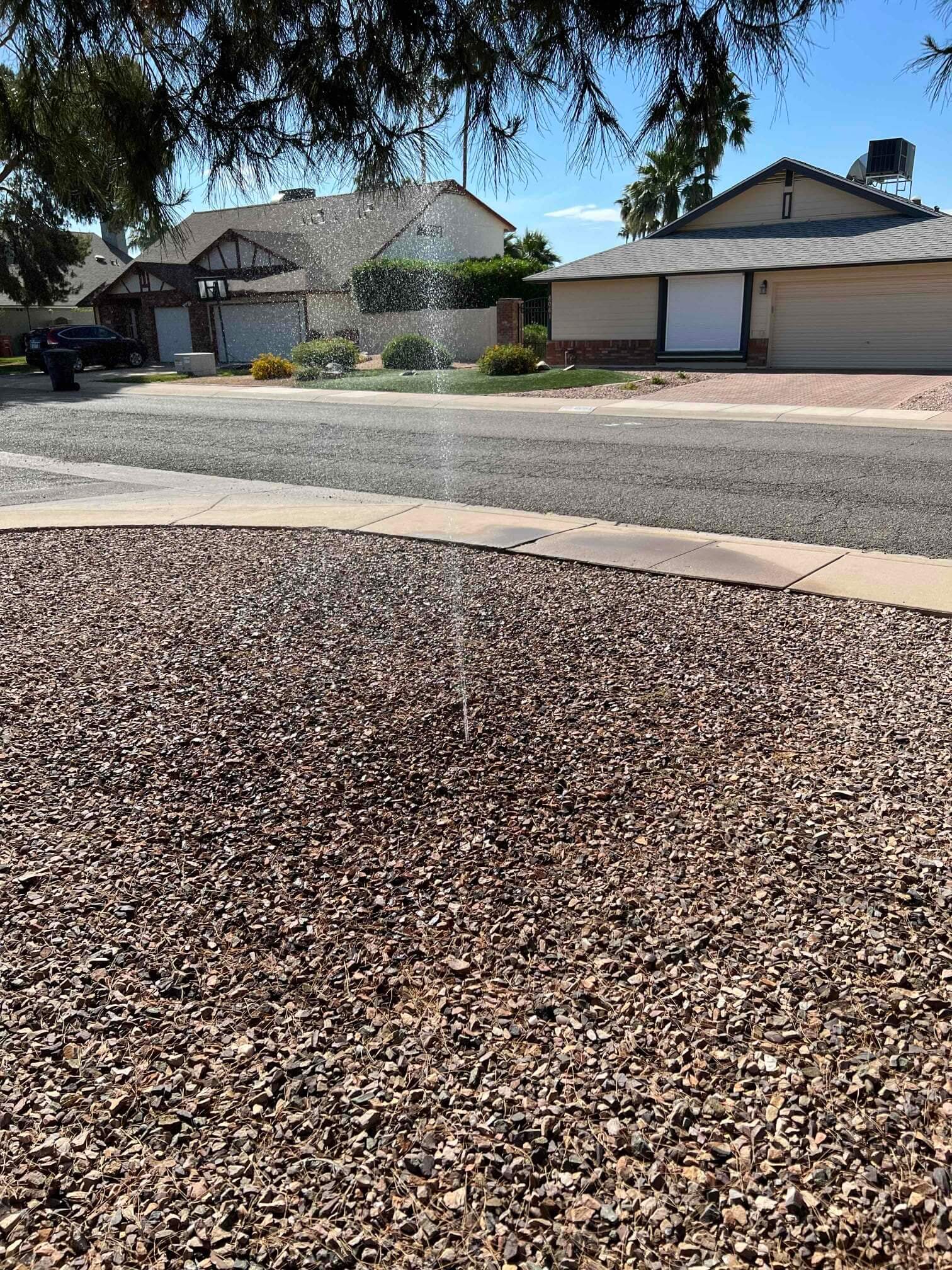 Sprinkler on gravel driveway, indicating irrigation leak repair service in the Phoenix Metro Area.<br />

